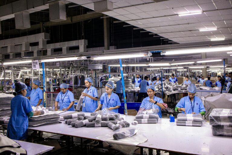 Group of blue collar workers organizing textiles in an Indian factory setting.